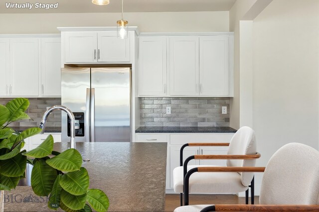 1606 Wyatt Earp Ct, Belgrade, MT 59714 - kitchen featuring stainless steel fridge, dark countertops, white cabinets, and tasteful backsplash