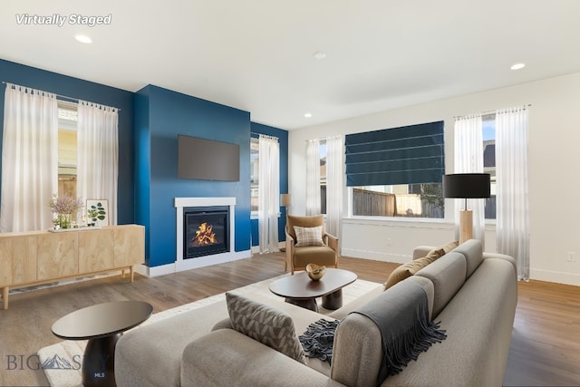 1606 Wyatt Earp Ct, Belgrade, MT 59714 - living room featuring wood finished floors, a glass covered fireplace, and recessed lighting