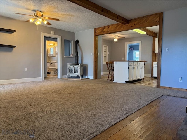 512 W 4th Ave, Big Timber, MT 59011 - unfurnished living room featuring a ceiling fan, a wood stove, and wood finished floors
