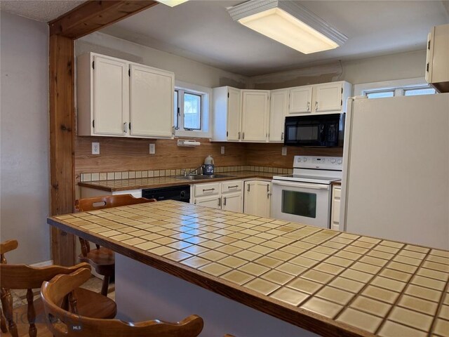 512 W 4th Ave, Big Timber, MT 59011 - kitchen with white appliances, tile counters, white cabinets, tasteful backsplash, and a breakfast bar area