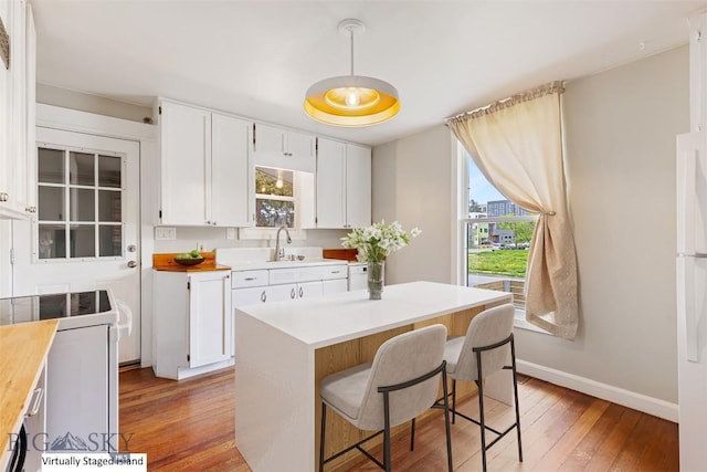 209 N 3rd Ave, Bozeman, MT 59715 - kitchen featuring stove, light wood-style flooring, white cabinets, a kitchen breakfast bar, and pendant lighting