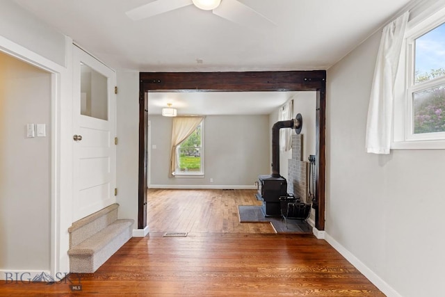 209 N 3rd Ave, Bozeman, MT 59715 - unfurnished living room with wood finished floors, plenty of natural light, ceiling fan, a wood stove, and beamed ceiling
