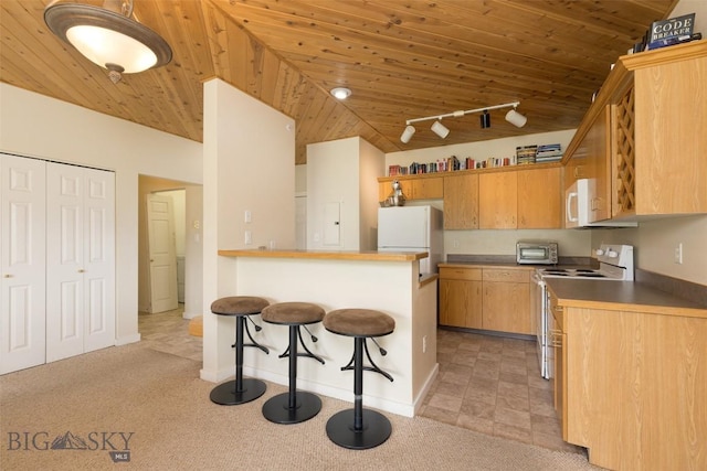 120 Firelight Dr Unit C10, Big Sky, MT 59716 - kitchen with white appliances, lofted ceiling, a kitchen bar, wood ceiling, and a peninsula