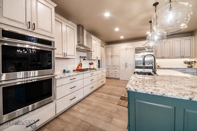 16 Tight Loop Dr, Bozeman, MT 59718 - kitchen with appliances with stainless steel finishes, wall chimney range hood, light wood-type flooring, backsplash, and light stone countertops