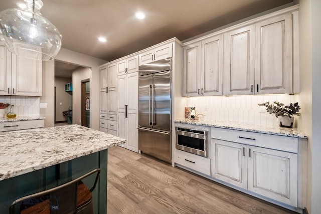 16 Tight Loop Dr, Bozeman, MT 59718 - kitchen with stainless steel built in refrigerator, tasteful backsplash, light wood-style flooring, recessed lighting, and light stone countertops
