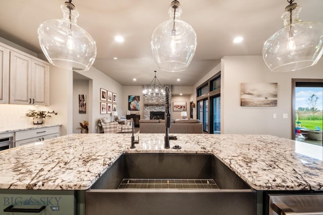 16 Tight Loop Dr, Bozeman, MT 59718 - kitchen with a stone fireplace, open floor plan, light stone countertops, recessed lighting, and decorative light fixtures