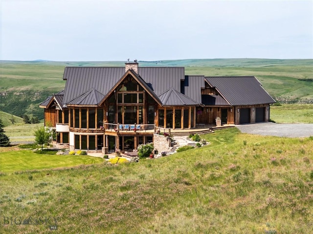 155 Peacemaker Ridge Rd, Belt, MT 59412 - rear view of house featuring driveway, an attached garage, a chimney, a metal roof, and a lawn