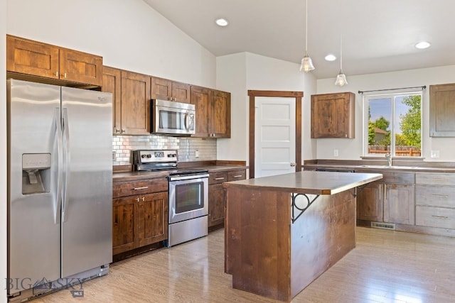 343 Stewart Loop, Bozeman, MT 59718 - kitchen with stainless steel appliances, vaulted ceiling, light wood-style flooring, backsplash, and a center island