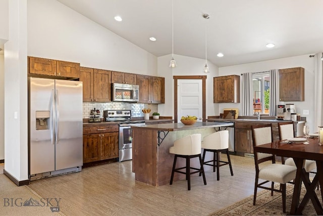343 Stewart Loop, Bozeman, MT 59718 - kitchen with stainless steel appliances, dark countertops, vaulted ceiling, a breakfast bar, and light wood-type flooring