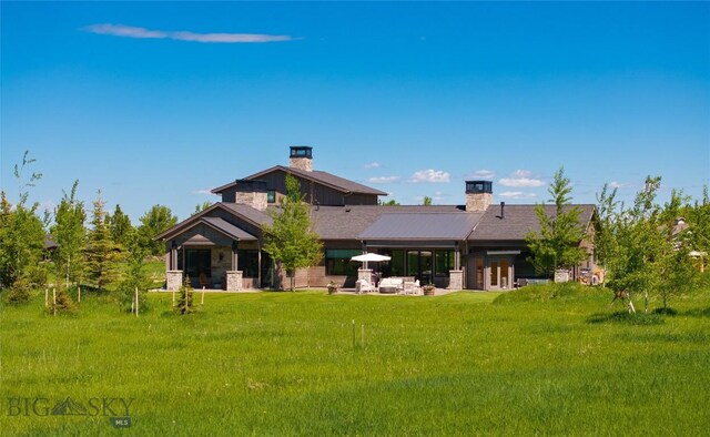 75 Vera Ct, Bozeman, MT 59718 - back of property with a chimney, a yard, a patio, and stone siding