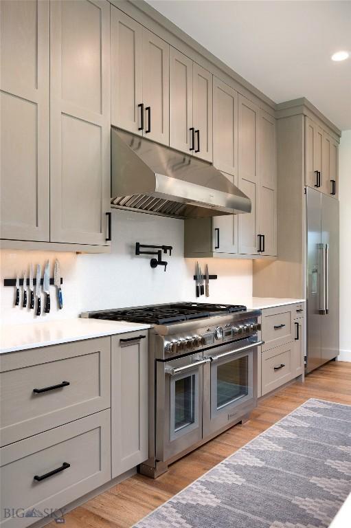 75 Vera Ct, Bozeman, MT 59718 - kitchen with under cabinet range hood, high end appliances, gray cabinets, light wood finished floors, and recessed lighting