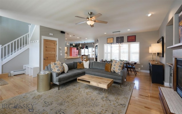 3214 Hillcrest Dr, Bozeman, MT 59715 - living area with stairway, a baseboard radiator, light wood-type flooring, a ceiling fan, and a glass covered fireplace