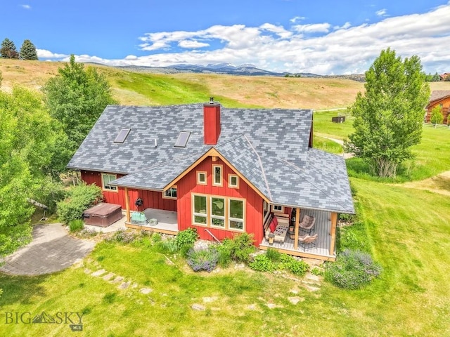 13 Blue Wing Rd, Ennis, MT 59729 - rear view of property featuring a wooden deck, board and batten siding, a chimney, roof with shingles, and a lawn