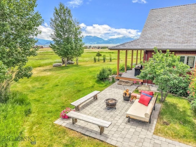 13 Blue Wing Rd, Ennis, MT 59729 - view of green lawn with a fire pit, a patio area, a deck with mountain view, and a view of countryside