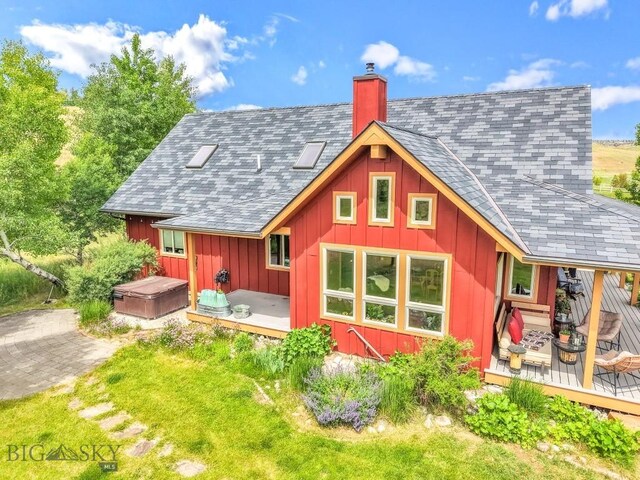 13 Blue Wing Rd, Ennis, MT 59729 - back of house with a hot tub, a deck, board and batten siding, and a chimney