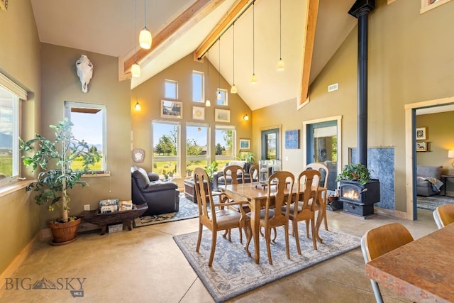 13 Blue Wing Rd, Ennis, MT 59729 - dining space with a wood stove, high vaulted ceiling, beamed ceiling, plenty of natural light, and concrete flooring