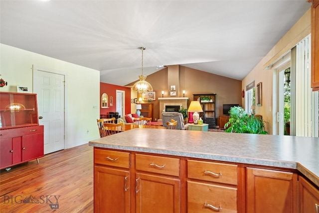 944 Forest Glen Dr, Bozeman, MT 59718 - kitchen with vaulted ceiling, a fireplace, light wood-style flooring, brown cabinets, and open floor plan