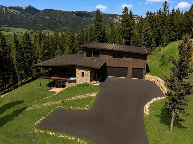 544 Grey Drake, Big Sky, MT 59716 - view of front facade with driveway, an attached garage, a front yard, a view of trees, and a mountain view