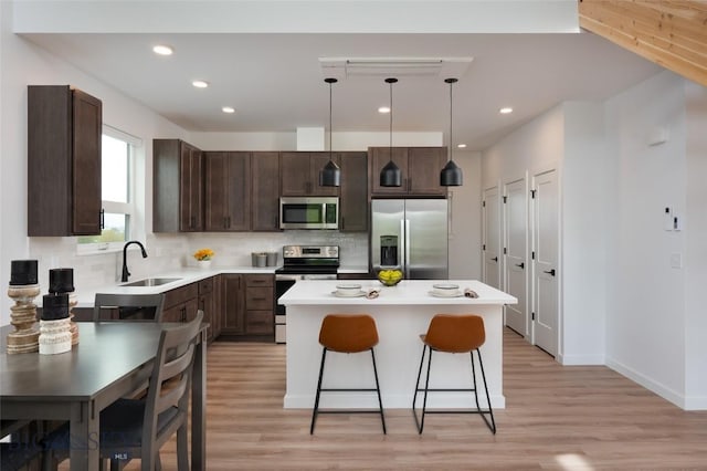 1942 Southbridge Unit B, Bozeman, MT 59718 - kitchen with appliances with stainless steel finishes, dark brown cabinetry, decorative backsplash, a kitchen island, and light wood finished floors