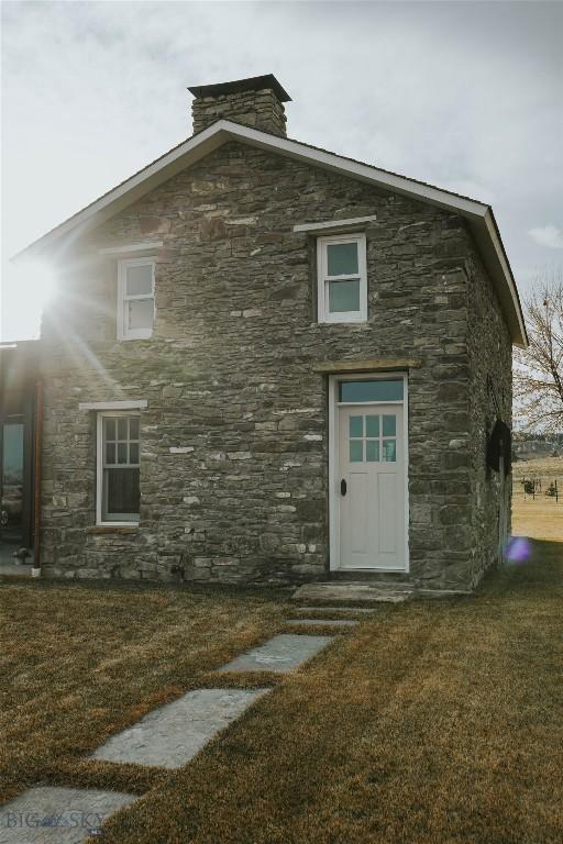 802 Deadmans Canyon Rd, Reed Point, MT 59069 - back of house with stone siding and a lawn