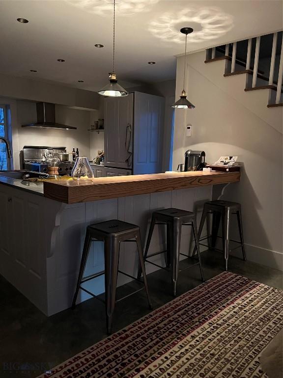 802 Deadmans Canyon Rd, Reed Point, MT 59069 - kitchen featuring wall chimney range hood, stove, a kitchen breakfast bar, pendant lighting, and a peninsula