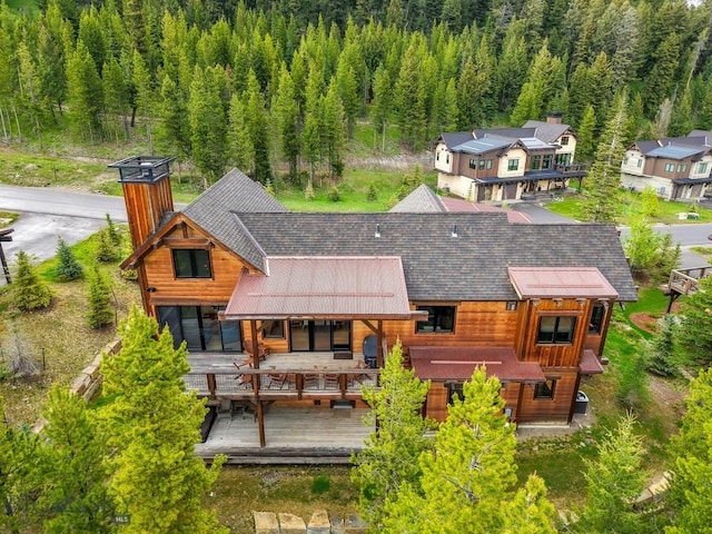 146 Outlook Trl, Big Sky, MT 59716 - rear view of property with a chimney, a forest view, roof with shingles, and a wooden deck