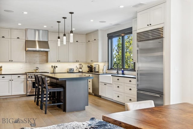 146 Outlook Trl, Big Sky, MT 59716 - kitchen with high end appliances, wall chimney exhaust hood, decorative backsplash, a kitchen island, and a kitchen breakfast bar