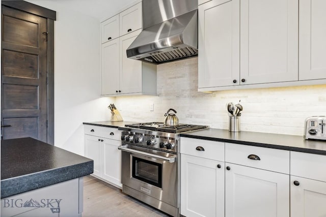 146 Outlook Trl, Big Sky, MT 59716 - kitchen with high end stainless steel range, wall chimney range hood, dark countertops, and tasteful backsplash