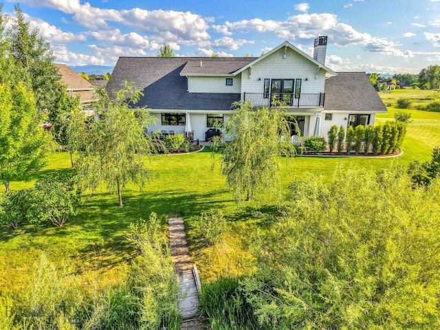 33 Oasis Trl, Bozeman, MT 59718 - rear view of property featuring a balcony, a lawn, roof with shingles, and a chimney