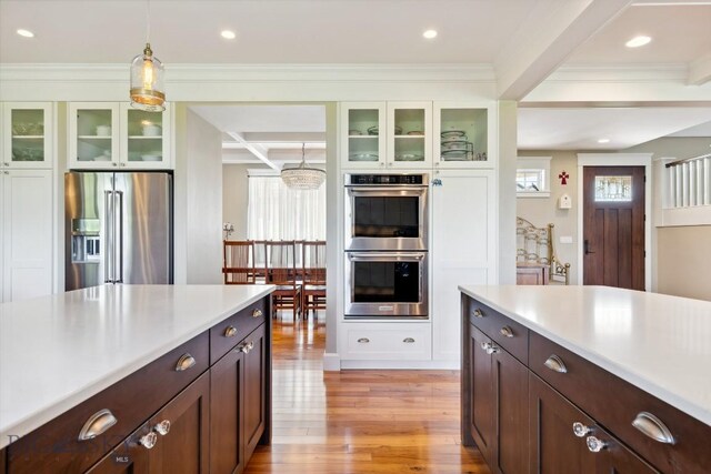 33 Oasis Trl, Bozeman, MT 59718 - kitchen with stainless steel appliances, light countertops, light wood-type flooring, coffered ceiling, and decorative light fixtures