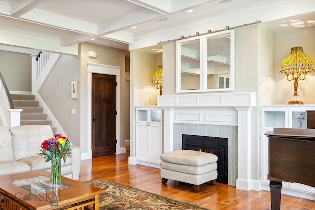 33 Oasis Trl, Bozeman, MT 59718 - living room featuring wood finished floors, coffered ceiling, beamed ceiling, a warm lit fireplace, and stairs
