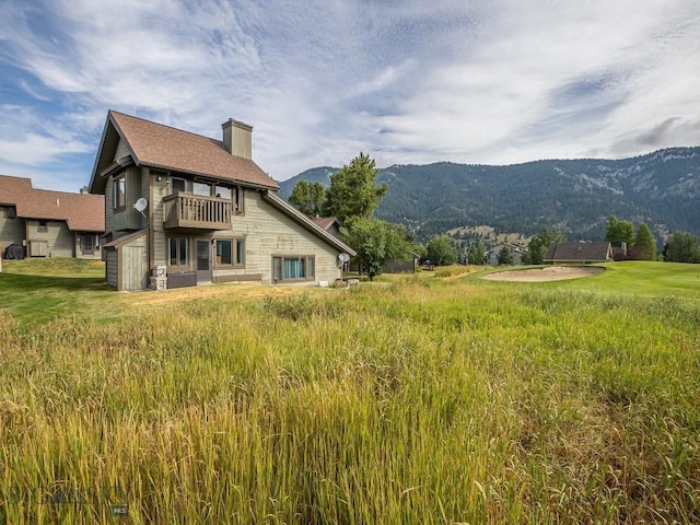20 Yellowstone Spur Rd Unit 20A, Big Sky, MT 59716 - rear view of house with a balcony, a mountain view, a chimney, and stone siding