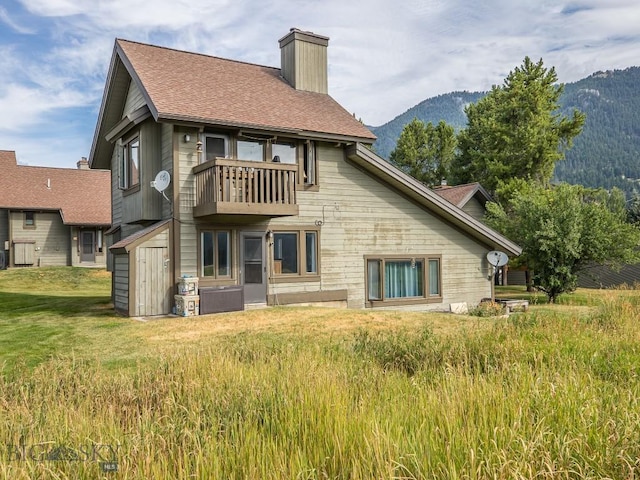 20 Yellowstone Spur Rd Unit 20A, Big Sky, MT 59716 - rear view of property featuring a chimney, a mountain view, a balcony, a storage unit, and a lawn