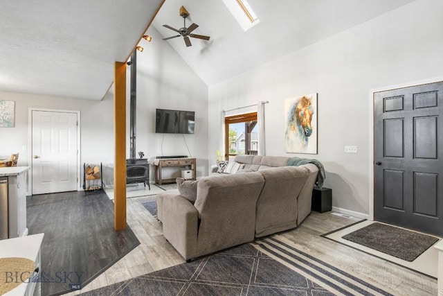 740 Linda Ln, Three Forks, MT 59752 - living area featuring high vaulted ceiling, a ceiling fan, dark wood-style floors, a wood stove, and a skylight