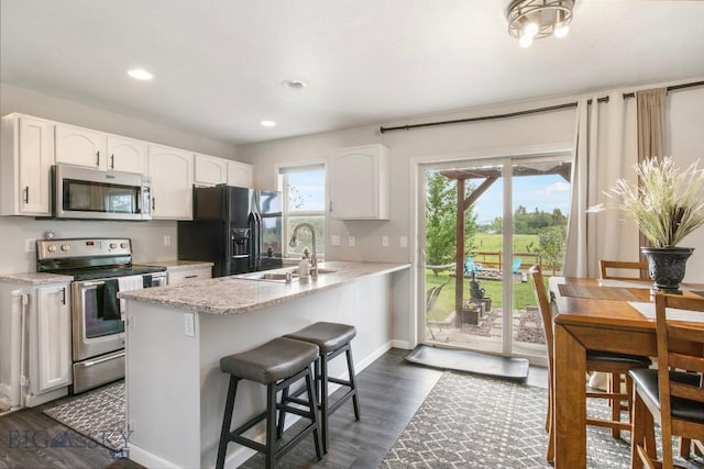 740 Linda Ln, Three Forks, MT 59752 - kitchen with appliances with stainless steel finishes, white cabinetry, a peninsula, dark wood-style flooring, and a kitchen bar