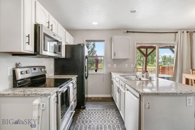 740 Linda Ln, Three Forks, MT 59752 - kitchen with stainless steel appliances, a peninsula, dark wood finished floors, white cabinets, and light stone counters