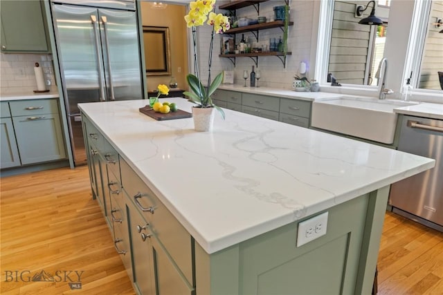 425 S Yellowstone St, Livingston, MT 59047 - kitchen with green cabinetry, stainless steel appliances, light wood-style floors, a center island, and decorative backsplash