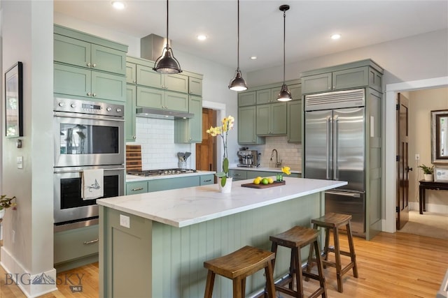 425 S Yellowstone St, Livingston, MT 59047 - kitchen with appliances with stainless steel finishes, green cabinetry, decorative backsplash, pendant lighting, and recessed lighting