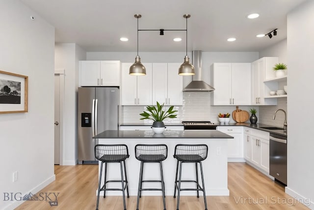 2221F Willow Unit 104, Livingston, MT 59047 - kitchen featuring stainless steel appliances, wall chimney range hood, open shelves, dark countertops, and a breakfast bar area