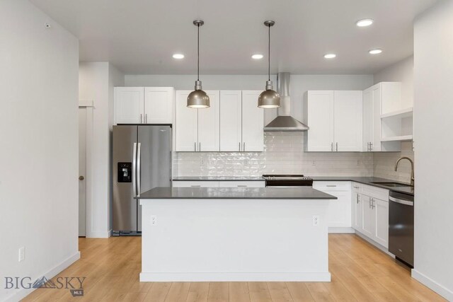 2221F Willow Unit 104, Livingston, MT 59047 - kitchen with appliances with stainless steel finishes, wall chimney range hood, dark countertops, a center island, and recessed lighting