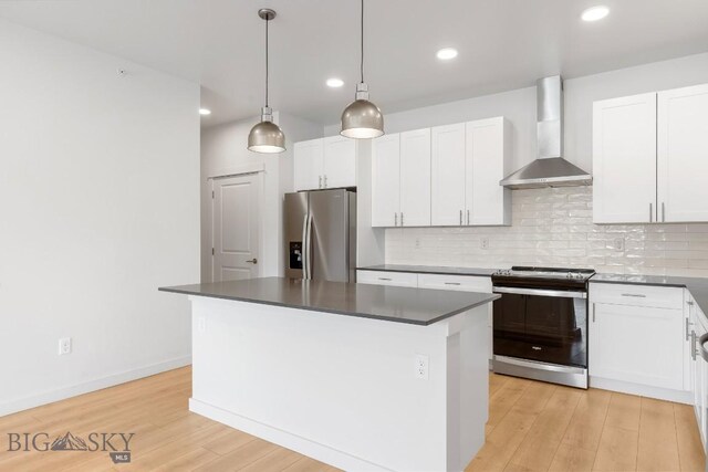 2221F Willow Unit 104, Livingston, MT 59047 - kitchen featuring stainless steel appliances, wall chimney range hood, a kitchen island, dark countertops, and tasteful backsplash