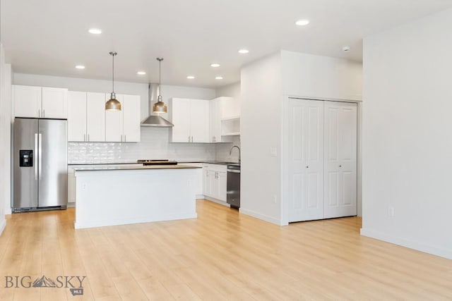2221F Willow Unit 104, Livingston, MT 59047 - kitchen with stainless steel appliances, wall chimney range hood, backsplash, white cabinets, and recessed lighting