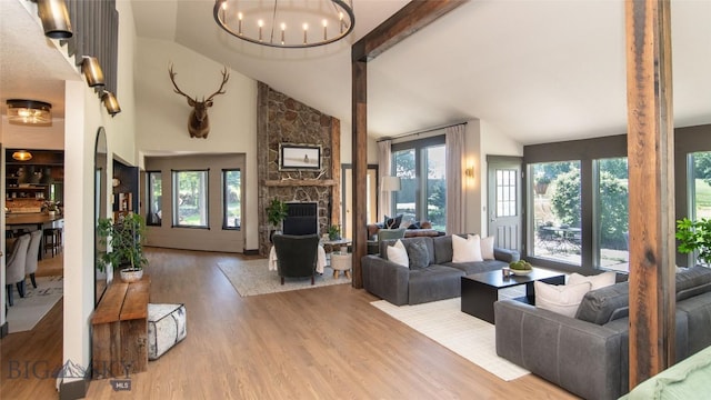 3640 Jagar Ln, Bozeman, MT 59718 - living room featuring plenty of natural light, a stone fireplace, wood finished floors, a chandelier, and high vaulted ceiling