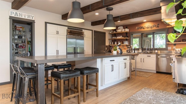 3640 Jagar Ln, Bozeman, MT 59718 - kitchen with stainless steel appliances, beamed ceiling, white cabinetry, light wood-style floors, and open shelves
