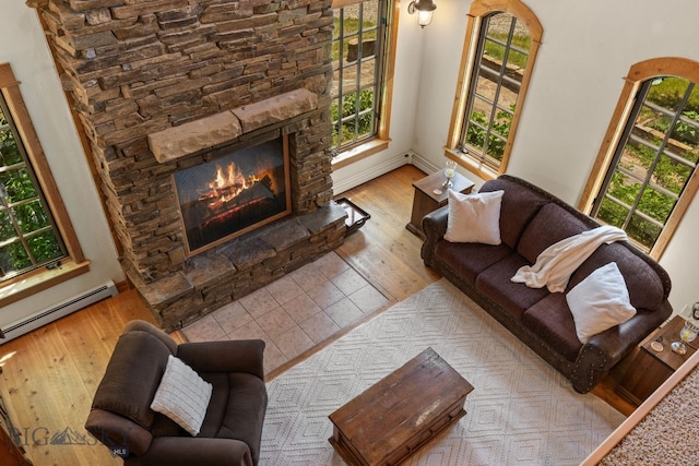 250 Silver Run Rd, Gallatin Gateway, MT 59730 - living room featuring wood finished floors, a fireplace, baseboard heating, and a baseboard radiator