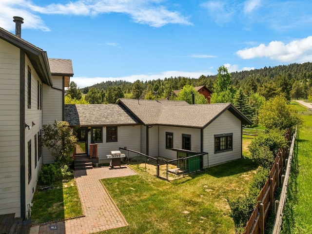 250 Silver Run Rd, Gallatin Gateway, MT 59730 - back of property with a wooded view, a patio, and roof with shingles