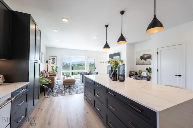 3083 S 27th Ave, Bozeman, MT 59718 - kitchen featuring light wood-type flooring, a kitchen island, hanging light fixtures, dark cabinetry, and open floor plan
