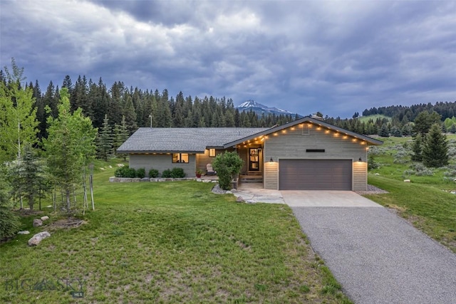 17 Chief Joseph Trl, Big Sky, MT 59716 - view of front facade with a garage, asphalt driveway, a front lawn, and a view of trees