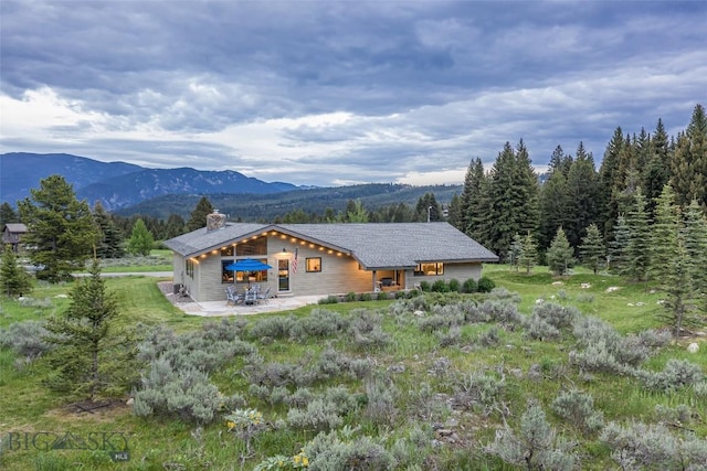 17 Chief Joseph Trl, Big Sky, MT 59716 - back of property with a chimney, a patio, and a mountain view