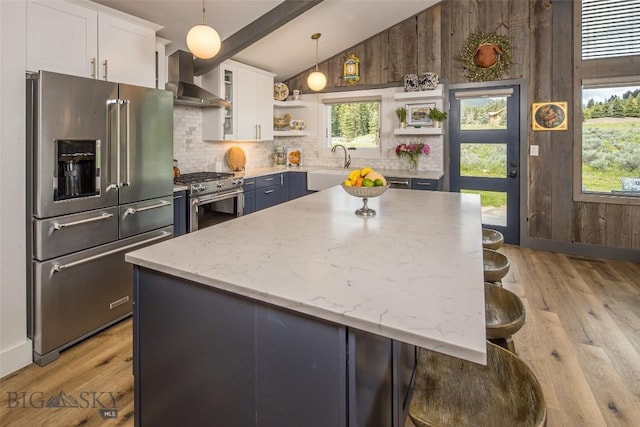 17 Chief Joseph Trl, Big Sky, MT 59716 - kitchen featuring premium appliances, wall chimney range hood, open shelves, light wood finished floors, and wood walls